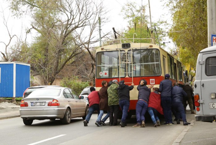 (imaginea zilei) Călători, surprinși pe o stradă cum împing un troleibuz de pe ruta 10